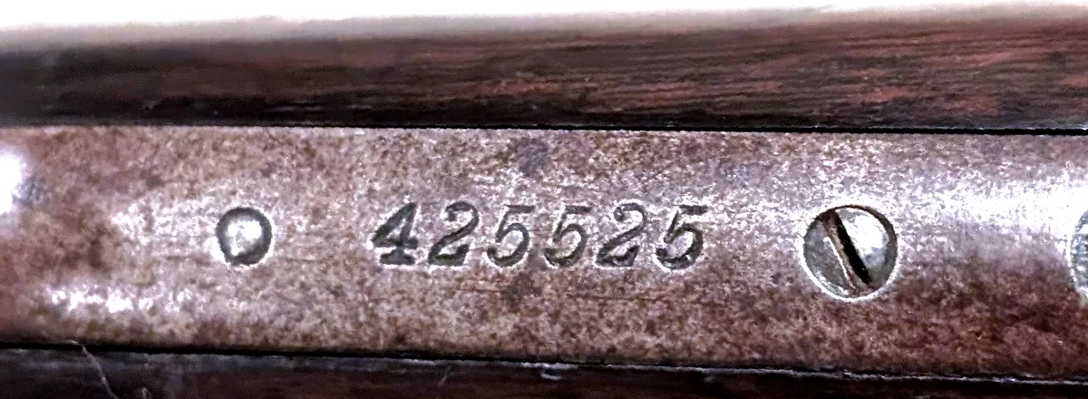 Close-up of the Winchester Model 1890 lower tang, behind the trigger guard, with the serial number 425525 stamped in the metal.