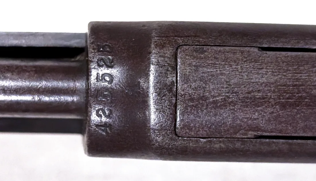 Close-up of the Winchester Model 1890 takedown joint with the serial number 425525 stamped vertically on the receiver face.